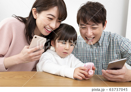 スマートフォンを持つ両親とキッズケータイを持つ5才の女の子　家族イメージ 63737045