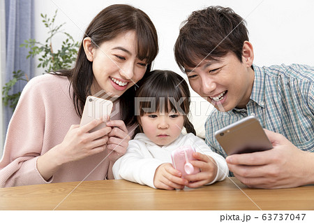 スマートフォンを持つ両親とキッズケータイを持つ女の子　家族イメージ 63737047