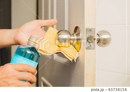 Hand cleaning door knob with alcohol and yellow microfiber cloth. Hand cleaning door knob with alcohol and yellow microfiber cloth. 63738158