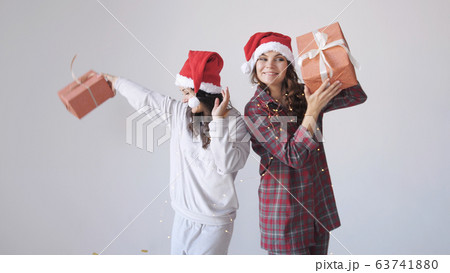 Happy women in Christmas cap shaking gift boxes. Concept of holidays 63741880