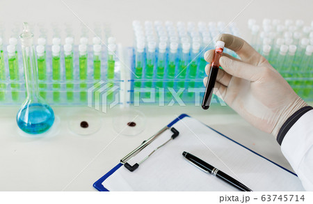 Close up photo of a doctor's hands with a test tube with a blood sample. 63745714