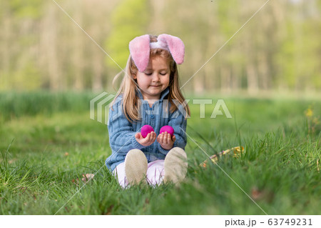 Girl with bunny ears collects the eggs for Easter 63749231