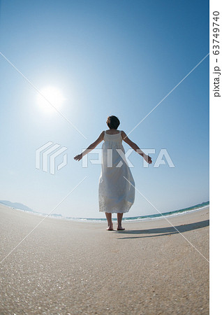 砂浜で空を見上げる女性の後ろ姿 63749740