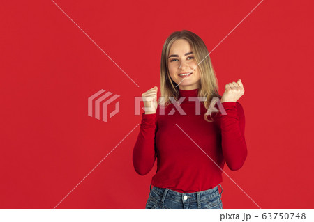 Monochrome portrait of young caucasian blonde woman on red background 63750748