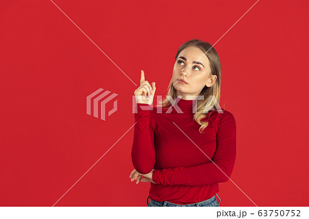 Monochrome portrait of young caucasian blonde woman on red background Monochrome portrait of young caucasian blonde woman on red background 63750752