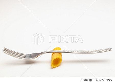 Penne pasta on the fork on the white table. 63751495