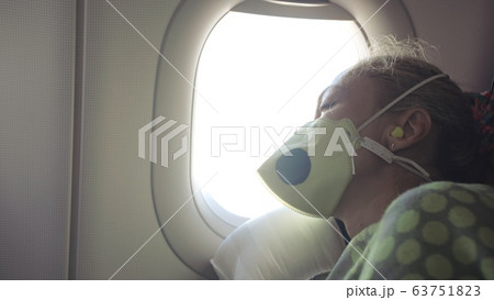 Woman travel caucasian at plane with wearing protective medical mask. Girl tourist at aircraft with respirator, feel bad and sleeps. Woman travel caucasian at plane with wearing protective medical mask. Girl tourist at aircraft with respirator, feel bad and sleeps. 63751823