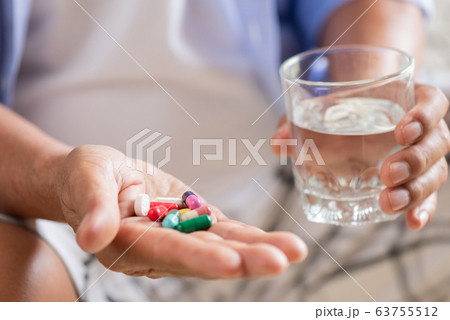 Asian old man taking in pill and another hand 63755512