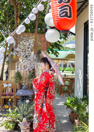The girl is wearing a red traditional kimono, which is the national dress of Japan and Hold an umbrella The girl is wearing a red traditional kimono, which is the national dress of Japan and Hold an umbrella 63756049