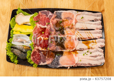 fresh slide bacon with beef pork and Shrimp, squid and mushrooms on tray ready to grill and cook on wood table in restaurant. Close up and select focus fresh slide bacon with beef pork and Shrimp, squid and mushrooms on tray ready to grill and cook on wood table in restaurant. Close up and select focus 63757208