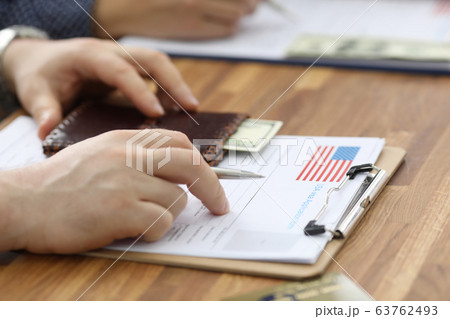 Male hands in suit lie on application for usa visa 63762493