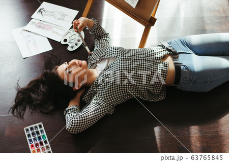woman dreaming laying on the floor with sketches 63765845