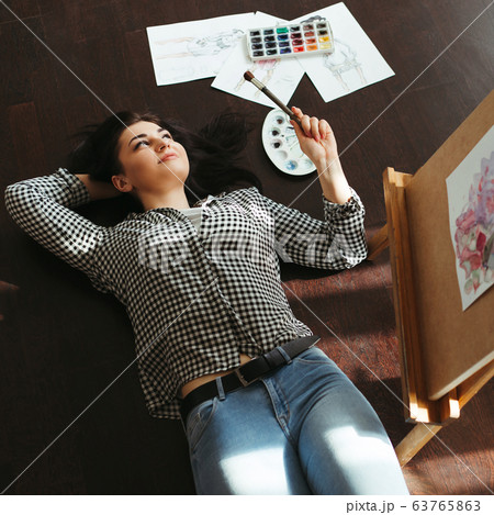 Woman dreaming laying on the floor with sketches 63765863
