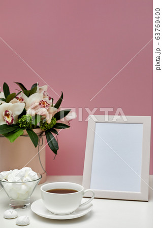 Front view blank mock up of photo frame on the pink background. orchid flowers, cup of tea and sweets. Space for text Front view blank mock up of photo frame on the pink background. orchid flowers, cup of tea and sweets. Space for text 63769400