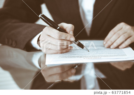 Unknown female hands with pen over document of contract. Agreement signing or business concept Unknown female hands with pen over document of contract. Agreement signing or business concept 63771854