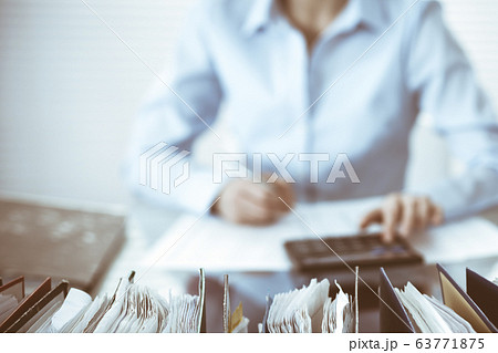 Binders of papers waiting to process by bookkeeper woman or financial inspector, close-up. Business portrait. Audit or tax concepts Binders of papers waiting to process by bookkeeper woman or financial inspector, close-up. Business portrait. Audit or tax concepts 63771875