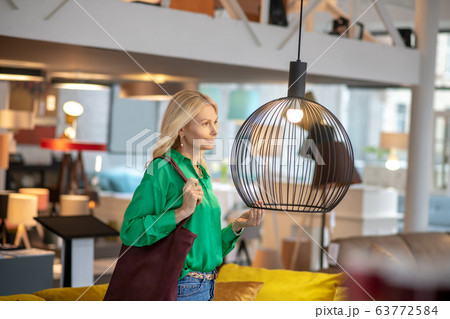 Blonde woman in a green blouse standing and looking at the bird 63772584