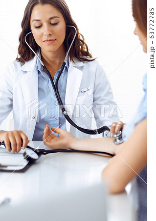 Doctor with a stethoscope in the hand examining her female patient. Health care, cardiology and medicine concepts Doctor with a stethoscope in the hand examining her female patient. Health care, cardiology and medicine concepts 63772785