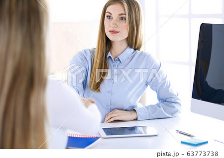 Business woman headshot while shaking hands with her female colleague or client in office. Casual clothes style of business people. Audit, tax or lawyer concept 63773738