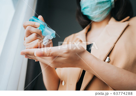 woman wearing face mask using alcohol gel woman wearing face mask using alcohol gel 63774288