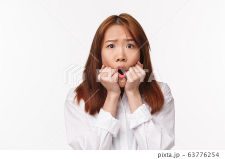 Close-up portrait of scared timid asian girl panicking, biting fingers looking afraid at camera, frowning and grimacing concerned, frightened watching interesting scary horror movie, white background Close-up portrait of scared timid asian girl panicking, biting fingers looking afraid at camera, frowning and grimacing concerned, frightened watching interesting scary horror movie, white background 63776254