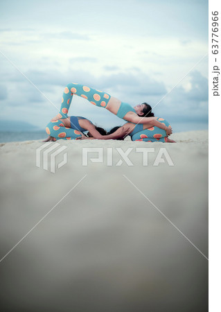 three woman playing yoga pose on sand beach three woman playing yoga pose on sand beach 63776966