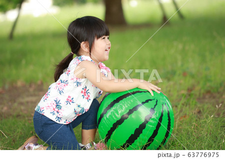 スイカのビーチボールで遊ぶ女の子の写真素材