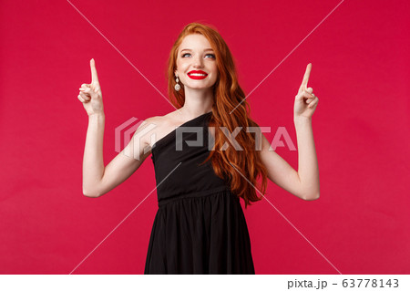 Celebration, events, fashion concept. Portrait of elegant and dreamy sensual redhead woman in black dress, pointing looking up with happy satisfied expression, found what she needs Celebration, events, fashion concept. Portrait of elegant and dreamy sensual redhead woman in black dress, pointing looking up with happy satisfied expression, found what she needs 63778143