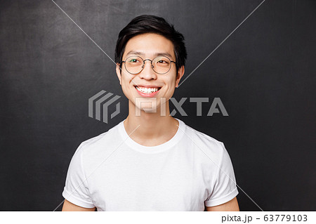 Close-up portrait of dreamy happy young asian man in white t-shirt, glasses, beaming smile excited, looking left cheerful, standing black background, remember something cute 63779103