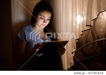 Stay home. Work home. Young woman sitting by the window and using digital tablet at home. Stay home. Work home. Young woman sitting by the window and using digital tablet at home. 63781818