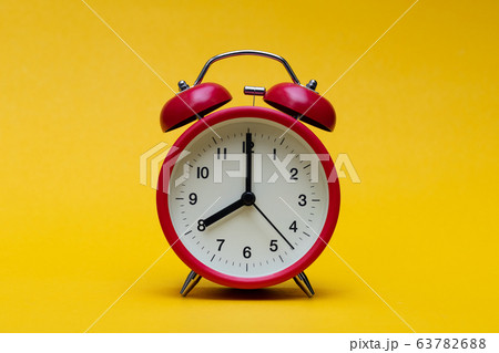Close up red alarm clock on yellow background Close up red alarm clock on yellow background 63782688