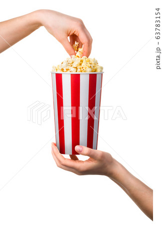 Woman hand taking popcorn from striped bucket Woman hand taking popcorn from striped bucket 63783154