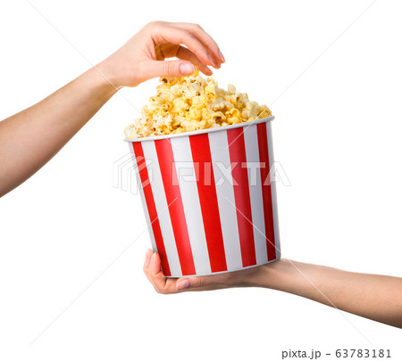 Woman hand taking popcorn from striped bucket 63783181