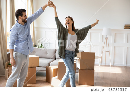 Happy young bearded man holding hand, twisting joyful wife. 63785557