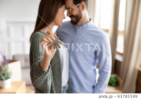 Focus on smiling young 30s woman showing keys on camera. 63785599
