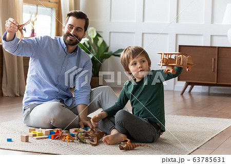 Little boy playing with wooden airplane, enjoying playtime with daddy. 63785631