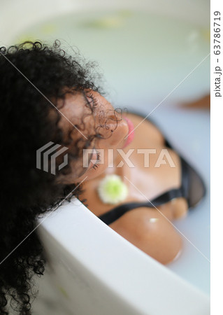 Portrait of curly haired black girl lying in milk bath and wearing bra. Portrait of curly haired black girl lying in milk bath and wearing bra. 63786719