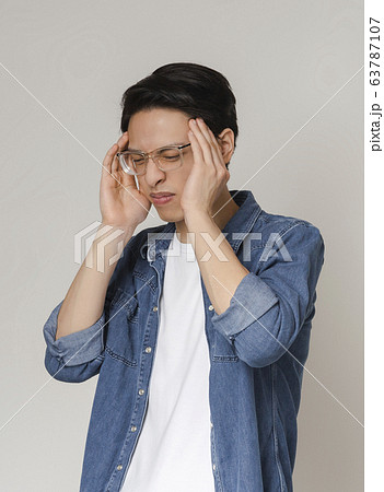 Asian man suffering from headache, touching his temples 63787107