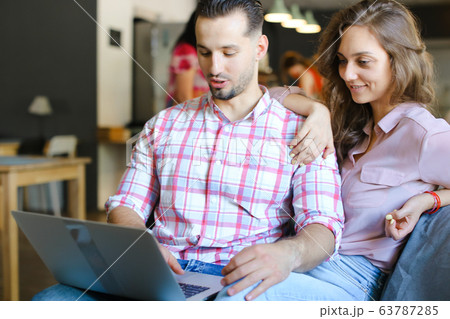 Young wife and husband using laptop at cafe and surfing. Young wife and husband using laptop at cafe and surfing. 63787285