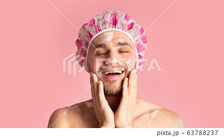 Funny guy in shower cap washing his face 63788237