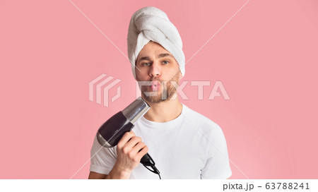 Man blows in hair dryer like in gun Man blows in hair dryer like in gun 63788241
