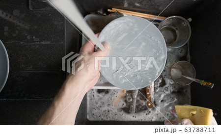 Washing dirty dishware in black sink 63788711