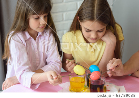Children stain eggs in a special dye in glasses 63789038