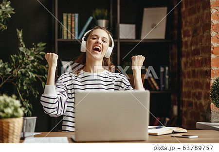 Happy woman celebrating achievement while working 63789757