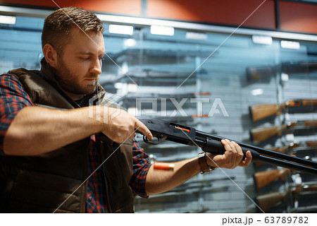 Man loads new rifle at counter in gun shop Man loads new rifle at counter in gun shop 63789782