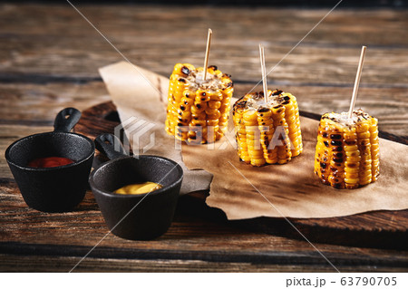 Grilled corn with sauces on a wooden background. Traditional american side dish, dark background, copy space. 63790705