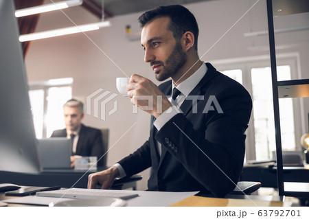 Caucasian man drinking tea at workplace in office Caucasian man drinking tea at workplace in office 63792701