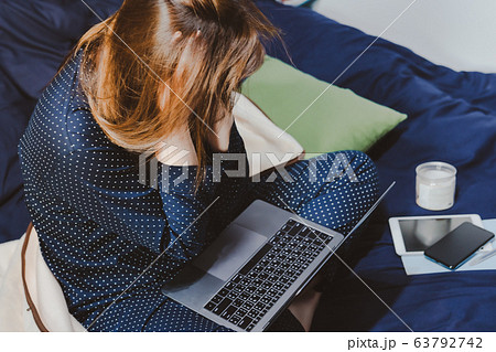 asian woman in classic blue pajama cloth work from home with serious feeling and sit on her bed for protect corona or COVID-19 virus 63792742