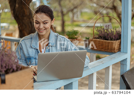 Smiling modern girl gazing at her laptop Smiling modern girl gazing at her laptop 63794104