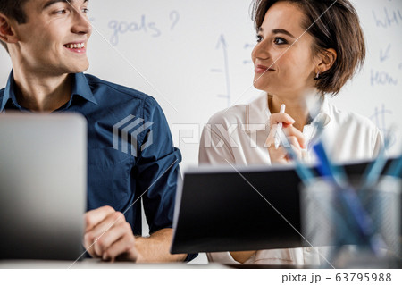 Smiling man and woman looking at each other in the office 63795988